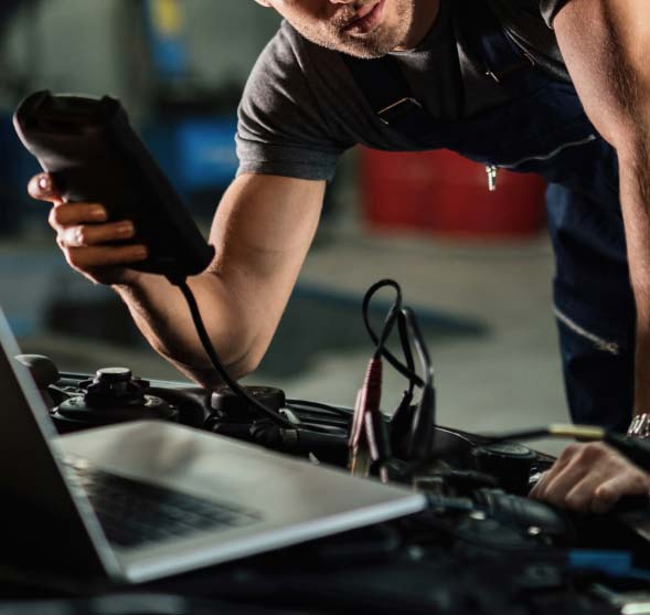 Mecánico utilizando equipo de diagnóstico conectado a un portátil en un taller automotriz